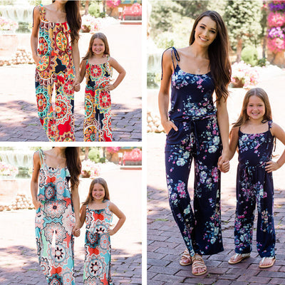 Woman wearing a navy blue floral wide-leg jumpsuit with pink and white flowers, tie-shoulder straps, and a drawstring waist.