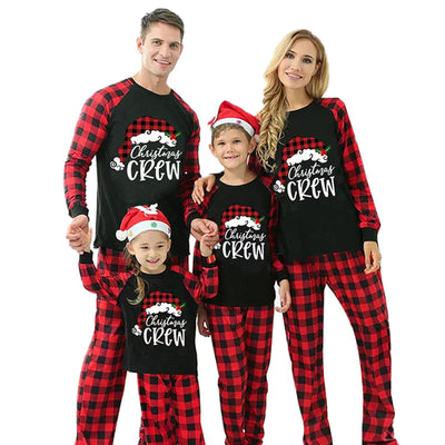 Family of four wearing matching red and black plaid Christmas pajamas with "Christmas CREW" graphic, children in Santa hats. - Image 4