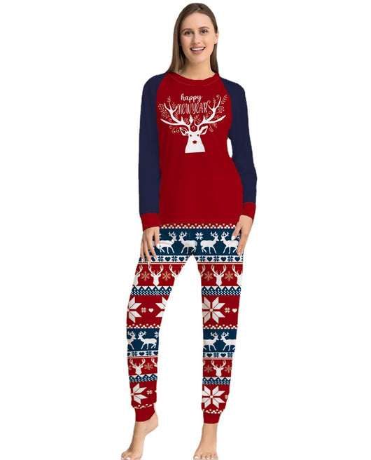 Child wearing a red and navy blue Christmas pajama set with a white reindeer and "happy NEW YEAR" text on the top, and fair isle pattern pants. - Image 2