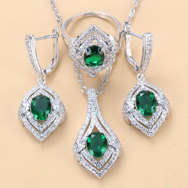 Silver-toned three-piece jewelry set with clear oval and round gems, including a necklace, dangle earrings, and a ring.