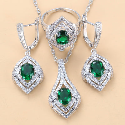 Silver-toned three-piece jewelry set with clear oval and round gems, including a necklace, dangle earrings, and a ring.