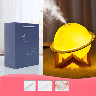Yellow planet-shaped humidifier with a wooden stand emitting mist, next to a dark blue celestial gift bag. - Image 7