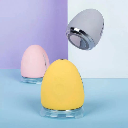 Yellow egg-shaped iontophoresis beauty instrument with a silver base and a power button on a white background. - Image 10