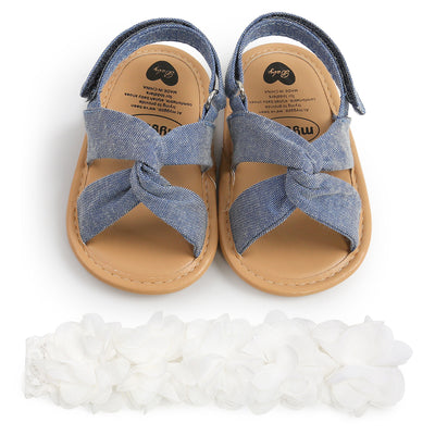 Black baby sandals with knotted cross straps and a matching black floral headband on a white background. - Image 14