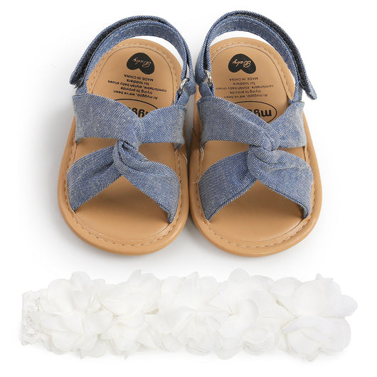 Black baby sandals with knotted cross straps and a matching black floral headband on a white background. - Image 14