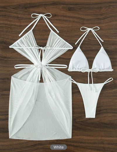 White three-piece halter neck bikini and sheer cover-up set with a heart-shaped embellishment, laid flat on wood. - Image 14
