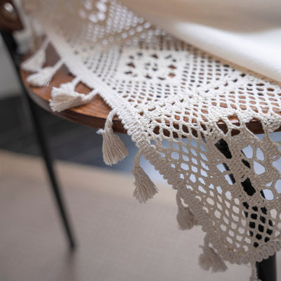 Close-up of a beige semi-transparent curtain with a delicate crochet lace trim and decorative tassels. - Image 31