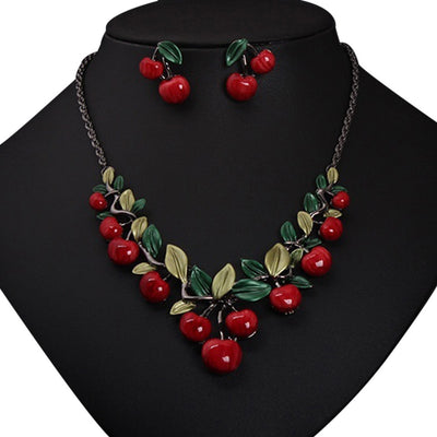 Cherry necklace and earring set featuring red enamel cherries and green leaves on a dark chain, displayed on a black bust. - Image 9