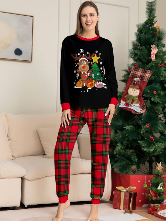 Two children in black and red plaid Christmas pajamas with a reindeer and Christmas tree graphic, standing by a Christmas tree. - Image 10