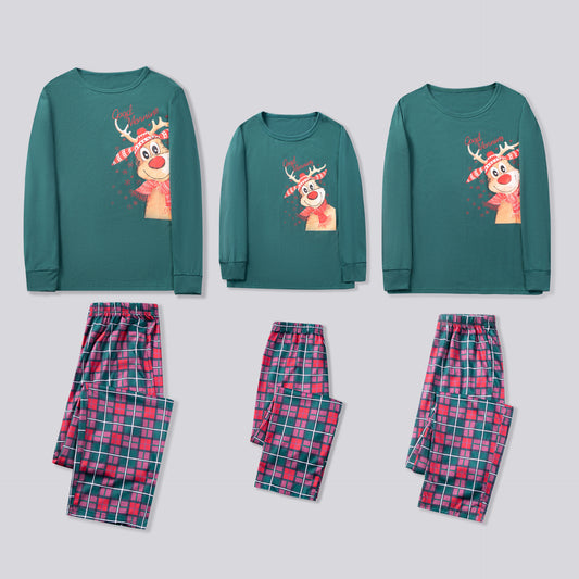 Family of five and a Boston Terrier wearing matching green long-sleeved Christmas pajamas with reindeer graphic and red plaid pants.