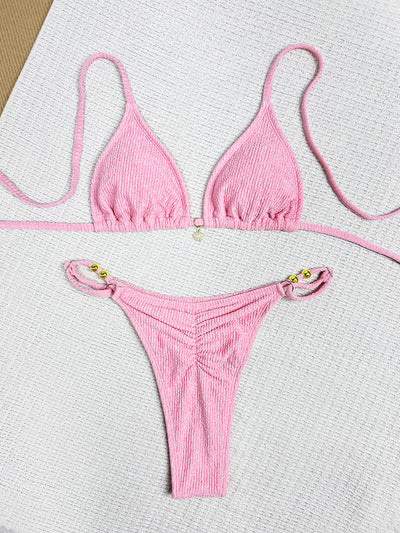 Pink textured halter bikini swimsuit with gold beads and a shell charm, worn by a woman on a wooden surface. - Image 12
