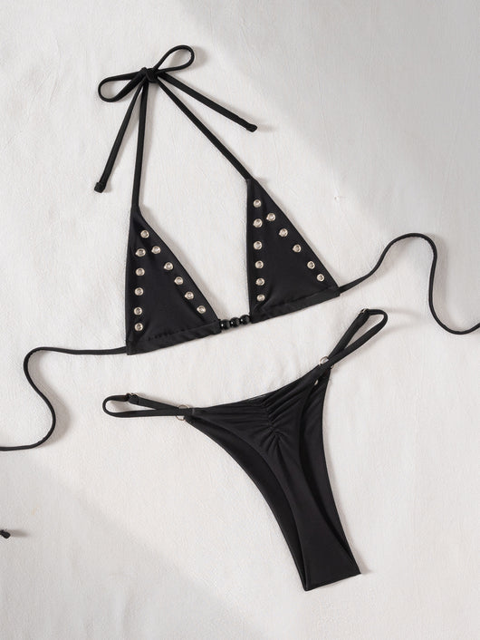 Black tie-front bikini swimsuit with silver grommets on the triangle top and a ruched thong bottom, laid flat. - Image 16