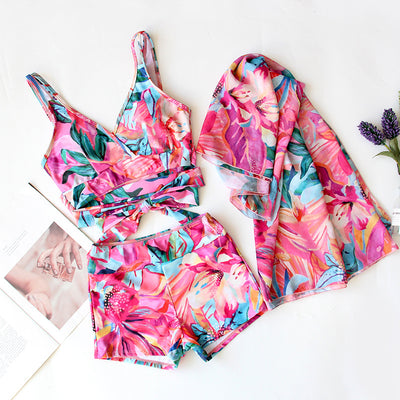 Women's three-piece swimwear set with a cream floral print, ruffled crop top, high-waisted shorts, and matching sarong. - Image 9