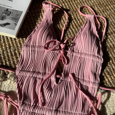 Woman in a light yellow ribbed one-piece tie-front backless bikini relaxing on a sandy beach by the ocean. - Image 22
