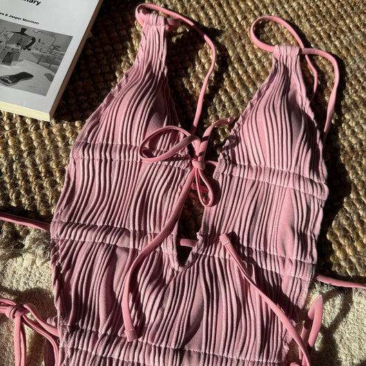 Woman in a light yellow ribbed one-piece tie-front backless bikini relaxing on a sandy beach by the ocean. - Image 22