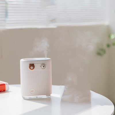 White cylindrical humidifier with ribbed texture, clear base, brown bear button, and silver dial, emitting mist on a white table. - Image 6