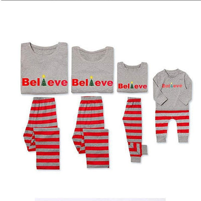 Family of four in matching grey long-sleeve tops and red striped pants, posing in a festive holiday setting. - Image 4