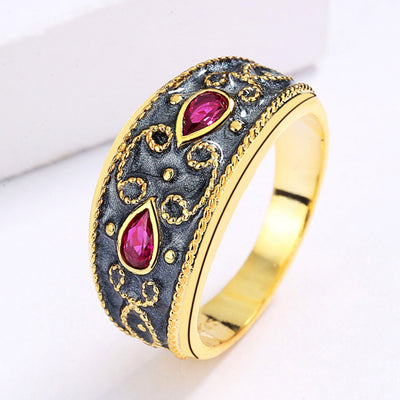 Gold-toned wide band ring with dark gray enamel, intricate scrollwork, and two fuchsia teardrop gemstones. - Image 2