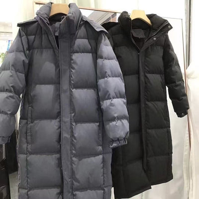 Black mid-length hooded down jacket with a quilted design, hanging on a metal rack in a store. - Image 8