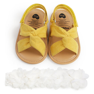 Black baby sandals with knotted cross straps and a matching black floral headband on a white background. - Image 11