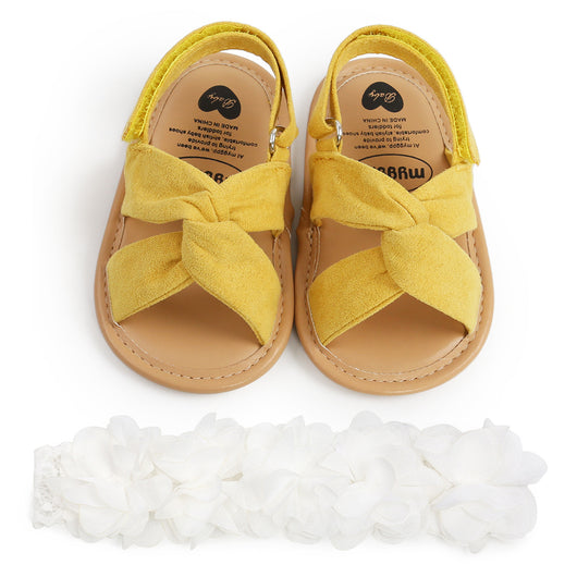 Black baby sandals with knotted cross straps and a matching black floral headband on a white background. - Image 11