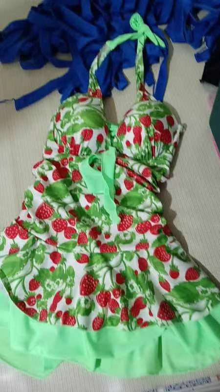 Woman wearing a white halter-neck swimsuit with a red strawberry and blue leaf pattern, featuring a dress-style skirt with a blue ruffled hem. - Image 14