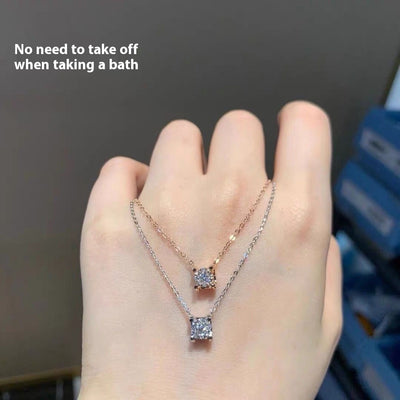 Delicate silver-colored chain necklace with a single square-cut clear stone pendant in a four-prong setting on a woman's neck.