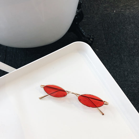 Silver-framed oval sunglasses with dark lenses reflecting a warm-toned object, displayed on a white tray. - Image 6