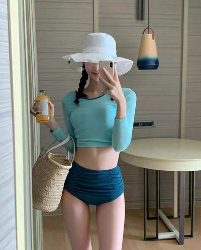 Woman in a pink long-sleeved crop top and black high-waisted ruched swim bottoms, posing in a mirror. - Image 6