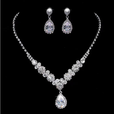 Sparkling silver-toned necklace and matching teardrop earrings set with clear stones, displayed on a black stand. - Image 8
