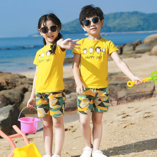 Family of four wearing matching yellow short-sleeved t-shirts with 'HAPPY DAY!' and geometric print shorts on a beach. - Image 12