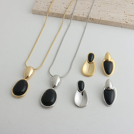 Pair of gold-toned irregular earrings with black onyx-like inserts, featuring a modern, abstract design.