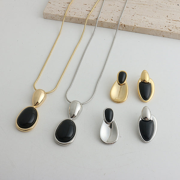 Pair of gold-toned irregular earrings with black onyx-like inserts, featuring a modern, abstract design.
