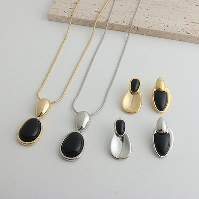 Pair of gold-toned irregular earrings with black onyx-like inserts, featuring a modern, abstract design.