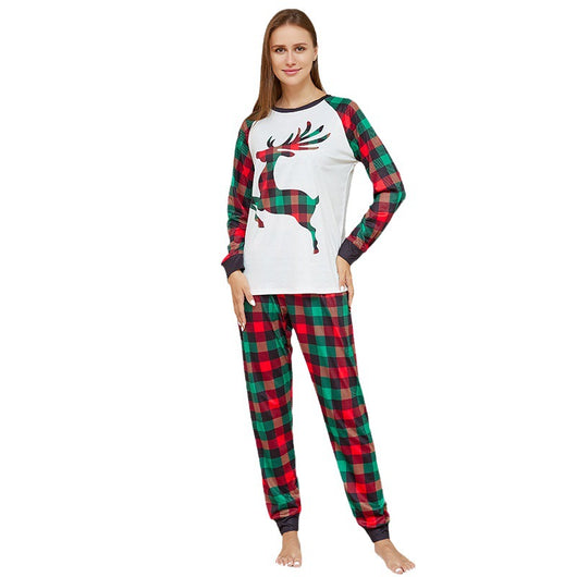Two children in matching red and green plaid Christmas pajamas with a reindeer graphic, standing by a Christmas tree. - Image 2