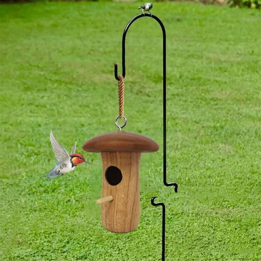 Wooden mushroom-shaped hummingbird feeder with a dark brown cap and light wood body, featuring an entrance hole and perch, held in a hand outdoors.