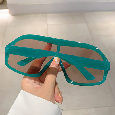 Oversized women's shield sunglasses with a tortoiseshell frame and brown-tinted lenses, held by a hand. - Image 9