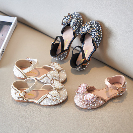Beige girls' shallow mouth pumps with a large pink pearl bow, glitter, and an ankle strap with a gold buckle. - Image 2