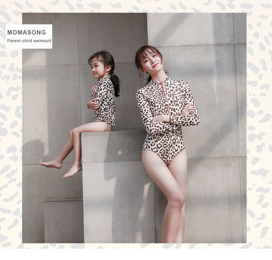 Child's long-sleeve leopard print swimsuit with a coral zipper and a matching swim cap on a white background. - Image 11