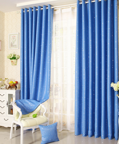 Blue star print curtains tied back to reveal sheer white curtains, in a bright room with a white chair. - Image 9