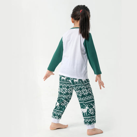 Woman in a Christmas pajama set with a white top, green sleeves, dinosaur graphic, and green fair isle pants. - Image 16