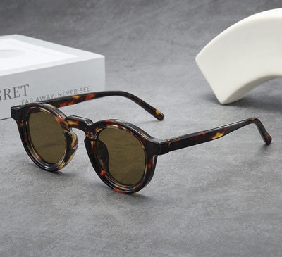 Vintage round frame sunglasses with black frames and pink lenses on a gray surface. - Image 11