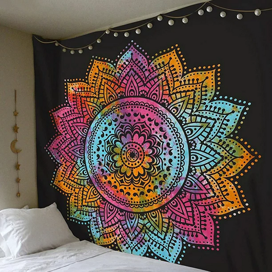 Vibrant multi-color mandala tapestry with a black background, hanging above a bed with white bedding.