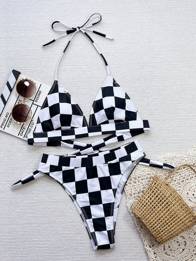 Women's black and white checkerboard print two-piece swimsuit with a halter top and high-waisted bottoms on a beach. - Image 6