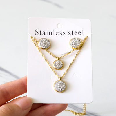 Gold plated stainless steel jewelry set with two layered necklaces and matching stud earrings. Features round crystal-studded pendants. - Image 6