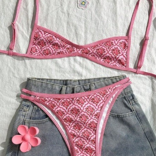 Pink two-piece bikini with a red floral and geometric print, featuring a bandeau top and high-cut bottoms.