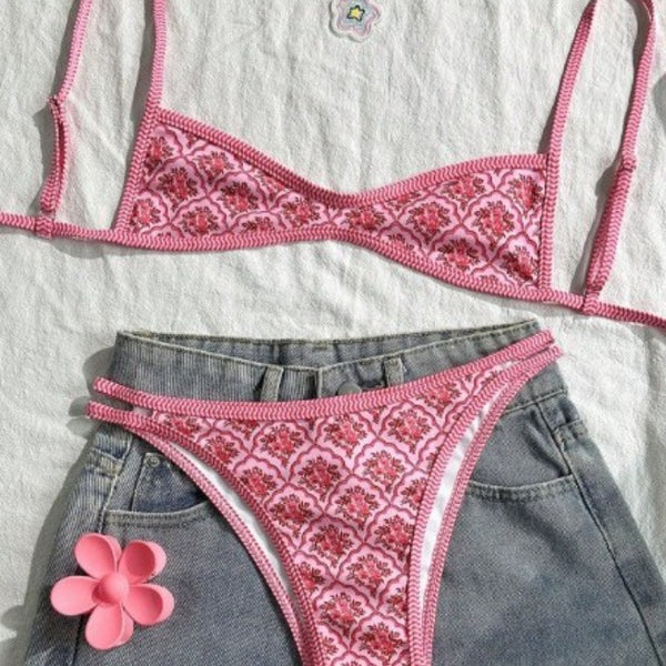 Pink two-piece bikini with a red floral and geometric print, featuring a bandeau top and high-cut bottoms.