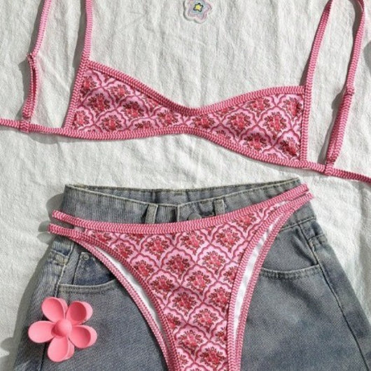 Pink two-piece bikini with a red floral and geometric print, featuring a bandeau top and high-cut bottoms.
