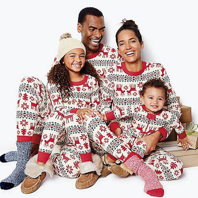 Family of four wearing matching red and white Christmas pajamas with reindeer and snowflake patterns, sitting with gifts. - Image 8