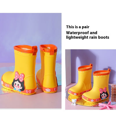 Bright yellow children's rain boots with a green cartoon dinosaur design and orange trim, held by hands. - Image 16